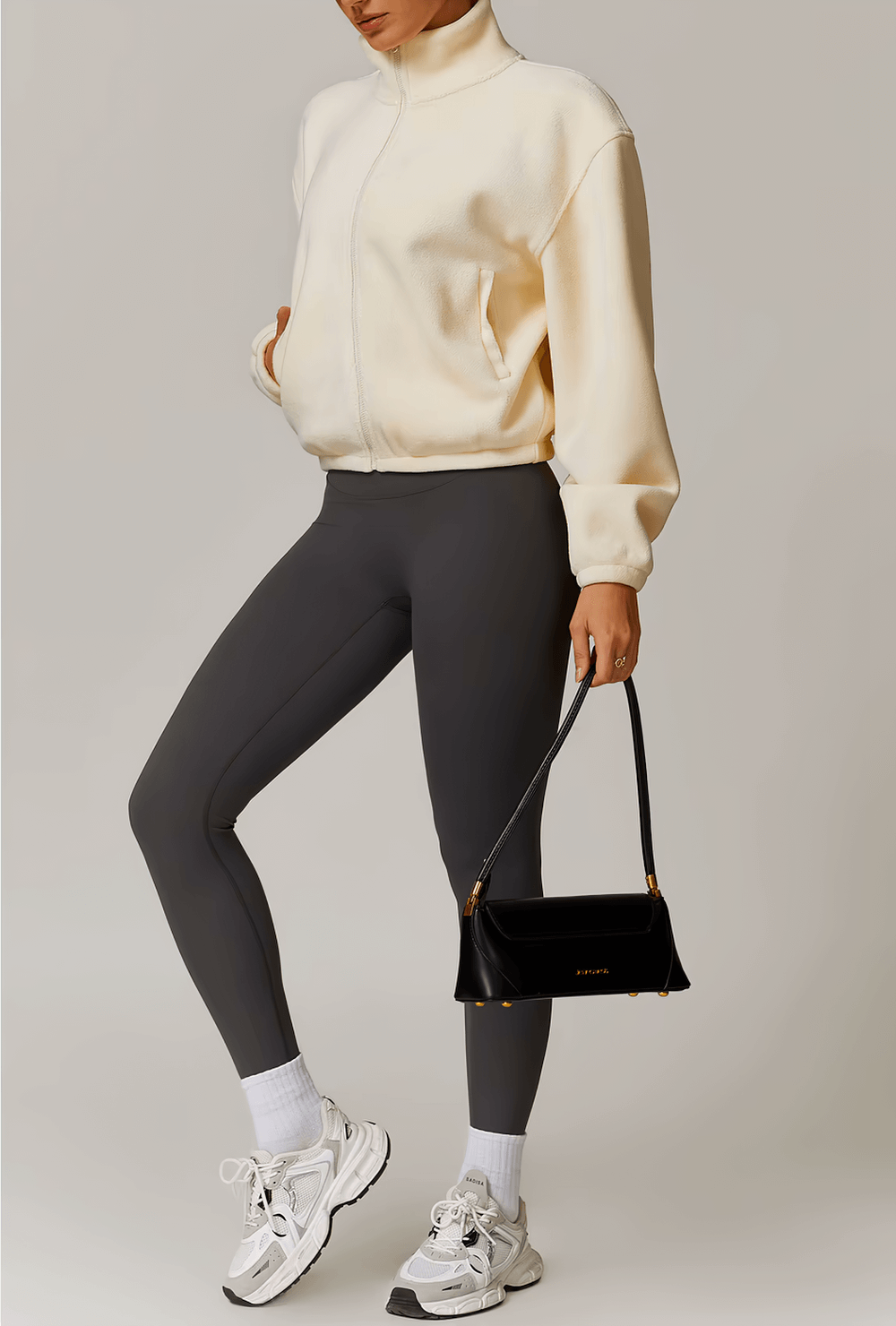 Alt Tag: Woman wearing stylish anti-pilling fleece jacket for running, paired with leggings and sneakers, holding a black purse.